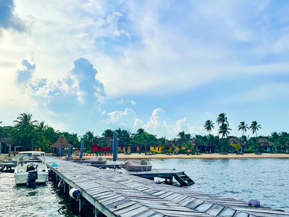 View of a beach with colorful buildings and palm trees against a blue sky, looking from a swimming dock.