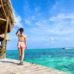 The blog author looking out at Belize's blue ocean while on a swimming dock.