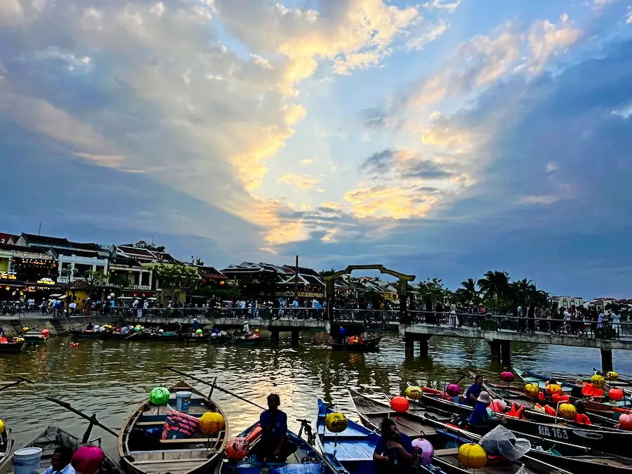 A river with many boats on it carrying round lanterns.